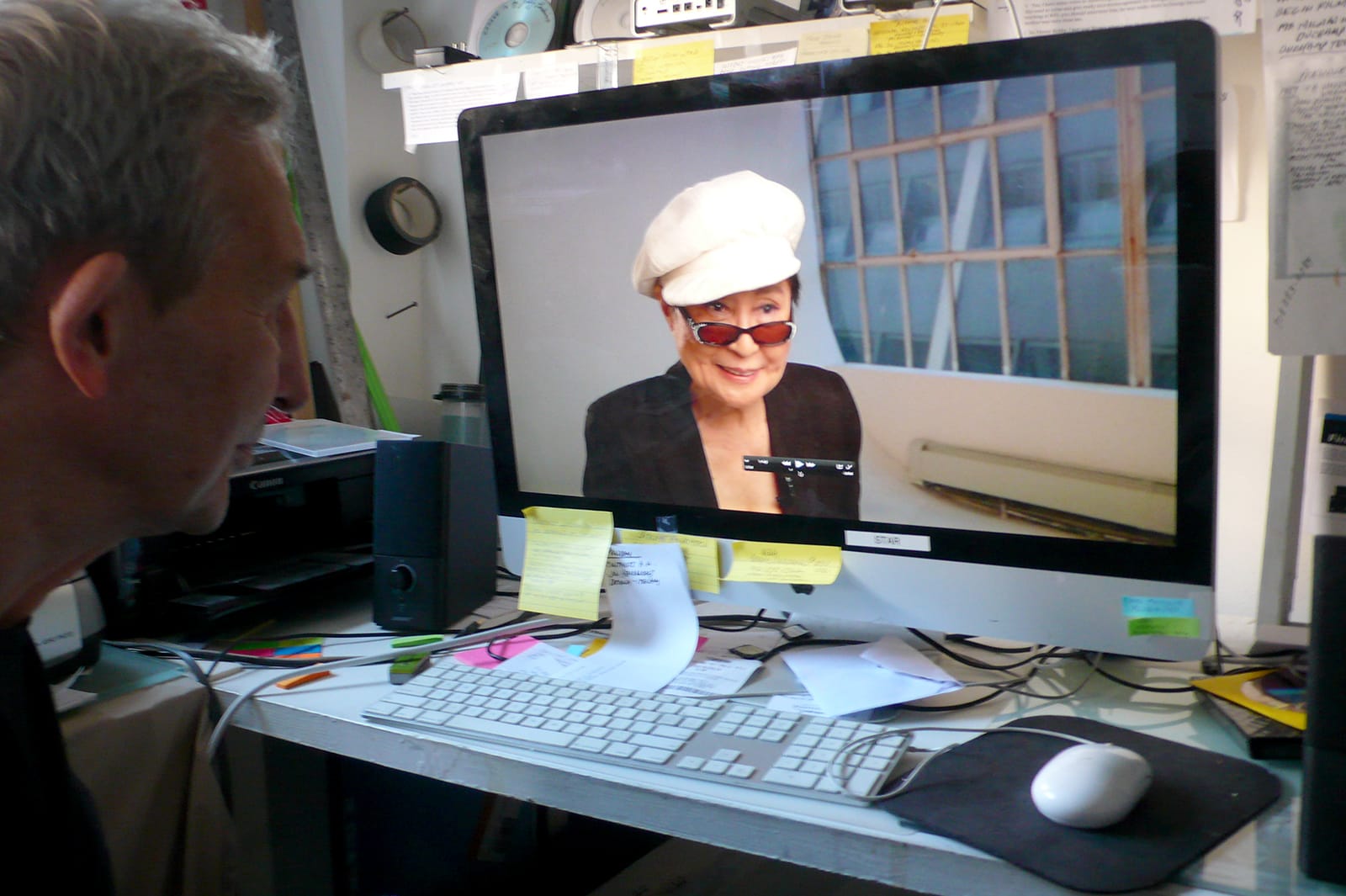 Jeffrey Perkins watches artist Yoko Ono in her interview for his film about George Maciunas (photo by Edward M. Gómez for Hyperallergic)