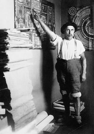 Adolf Wölfli in his room at the Waldau Psychiatric Clinic near Bern, Switzerland, in 1921, with a stack of his handmade, illustrated books (© Adolf Wölfli Foundation, Kunstmuseum Bern)