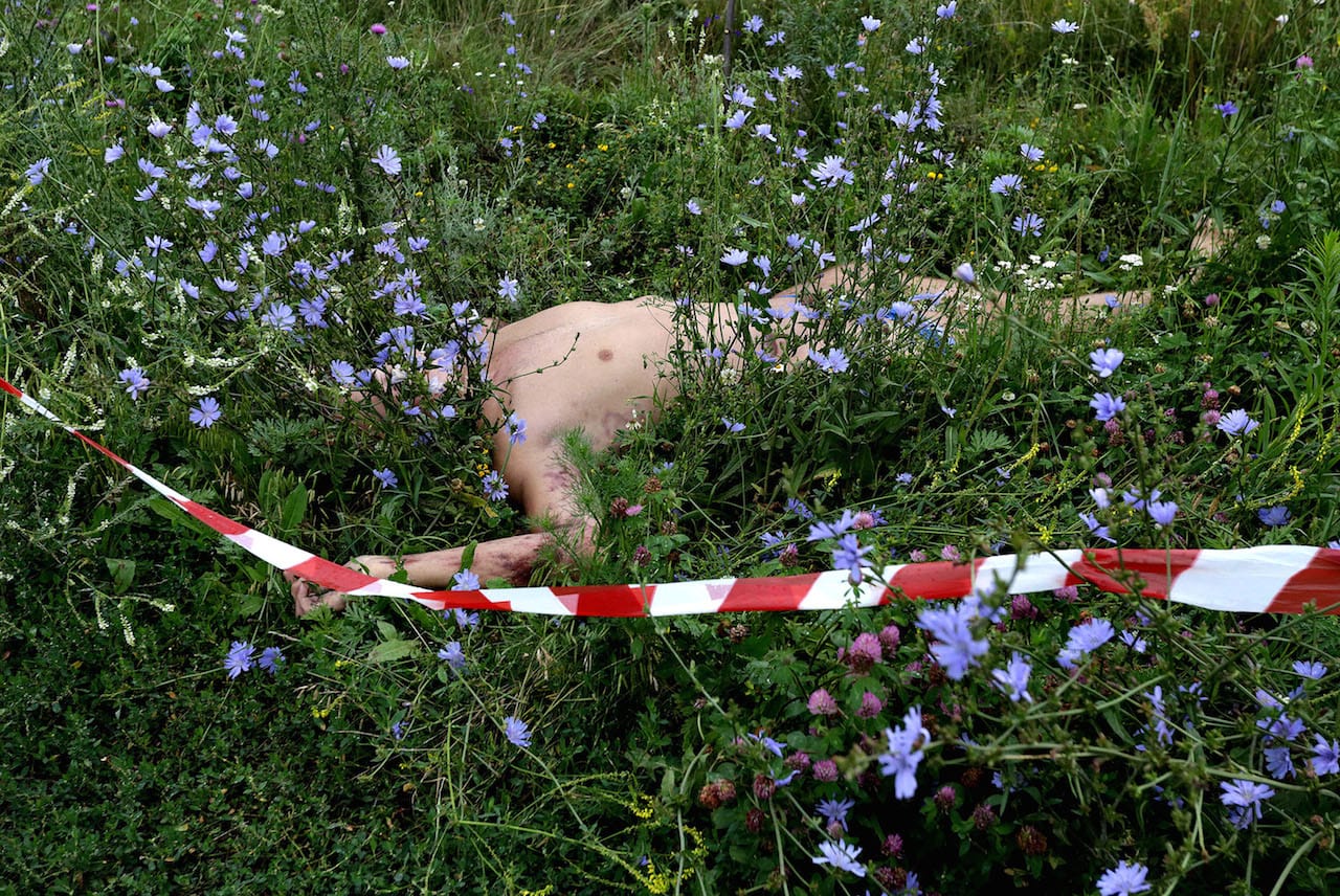 The body of one of the passengers is marked with barrier tape near the crash site of the Boeing 777, Malaysia Airlines flight MH17, which crashed during flying over the eastern Ukraine region near Donetsk, Ukraine. A Malaysia Airlines plane with 295 people on board crashed at 17 July in eastern Ukraine, and both the government and separatist rebels fighting in the area denied shooting it down. All passengers on board Flight MH17 from Amsterdam to Kuala Lumpur are feared dead. © Anastasia Vlasova.