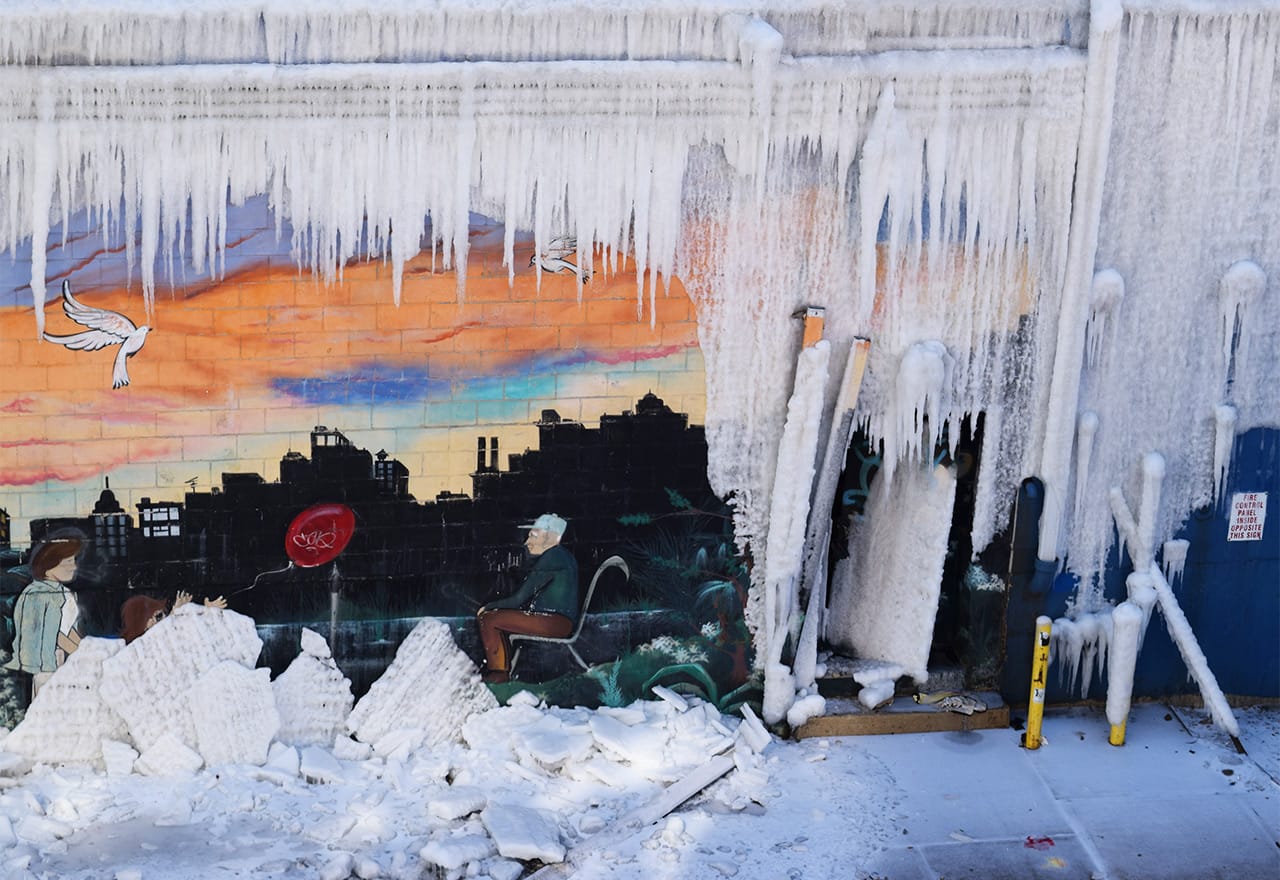 A mural on the burnt warehouse's exterior, encased in ice