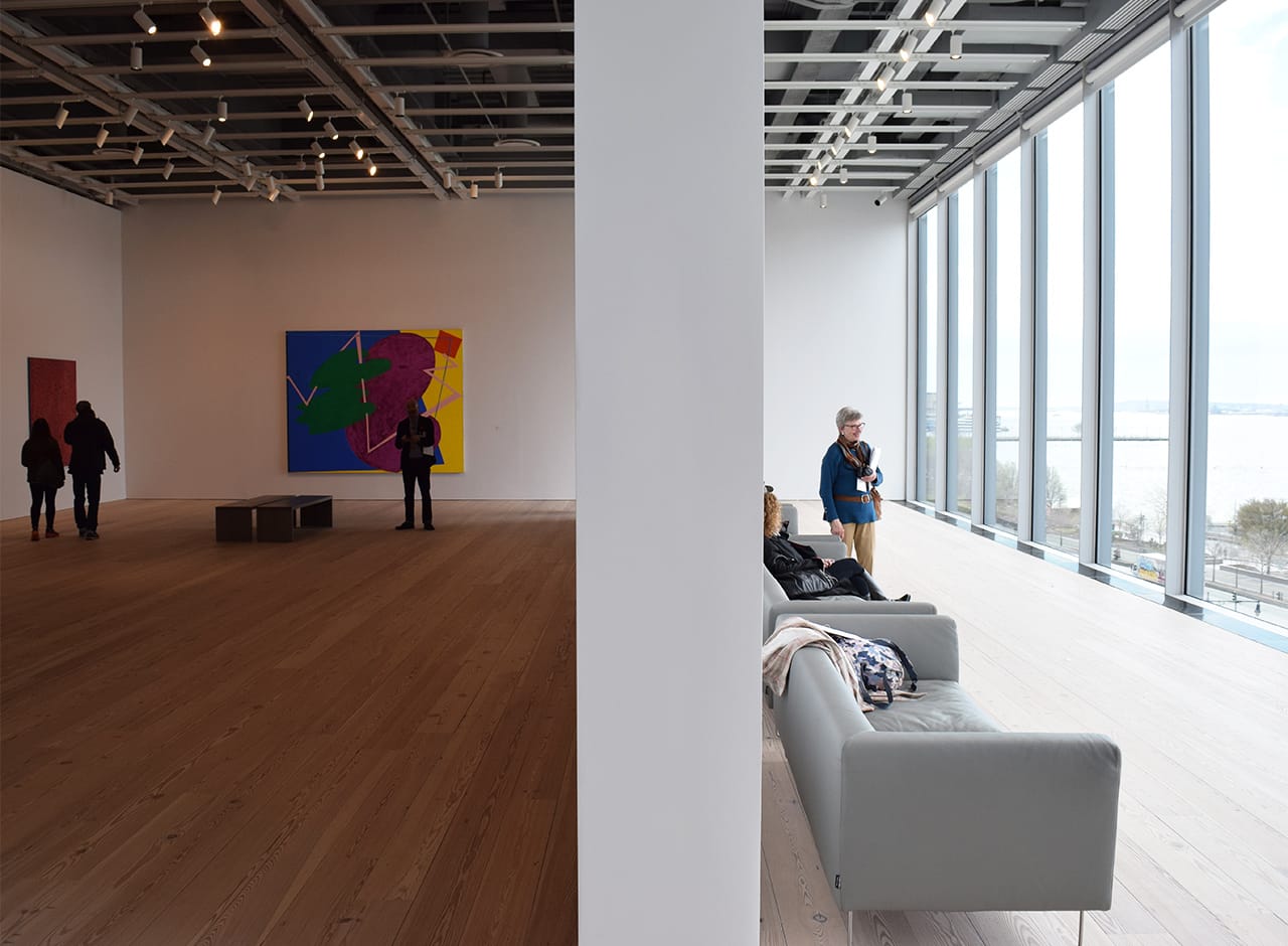 On the fifth floor, couches face a wall of glass that looks out onto the Hudson, allowing some natural light to filter through to the adjacent galleries