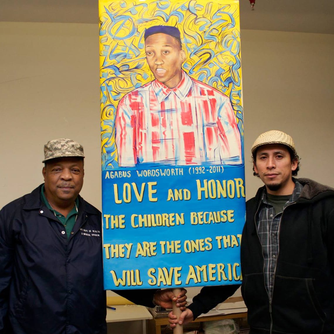 People's Climate Arts member Raul Ayala with Emboya Wordsworth who lost his son to Police Brutality. Sign made by Raul for O22 day of action. (photo courtesy People's Climate Arts)