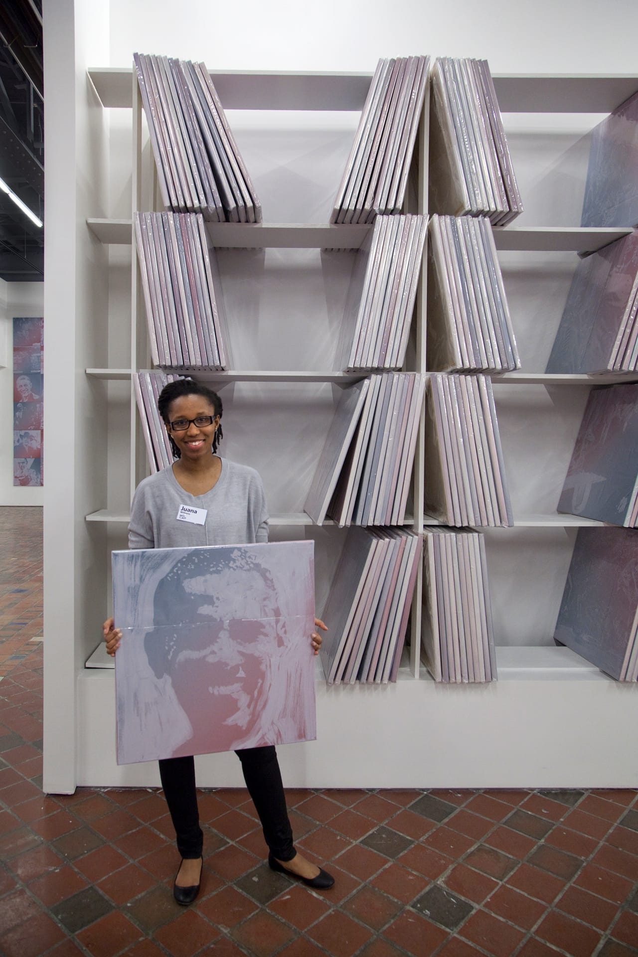 MOCAD intern Juana Williams handles an individual painting from the collection wall.