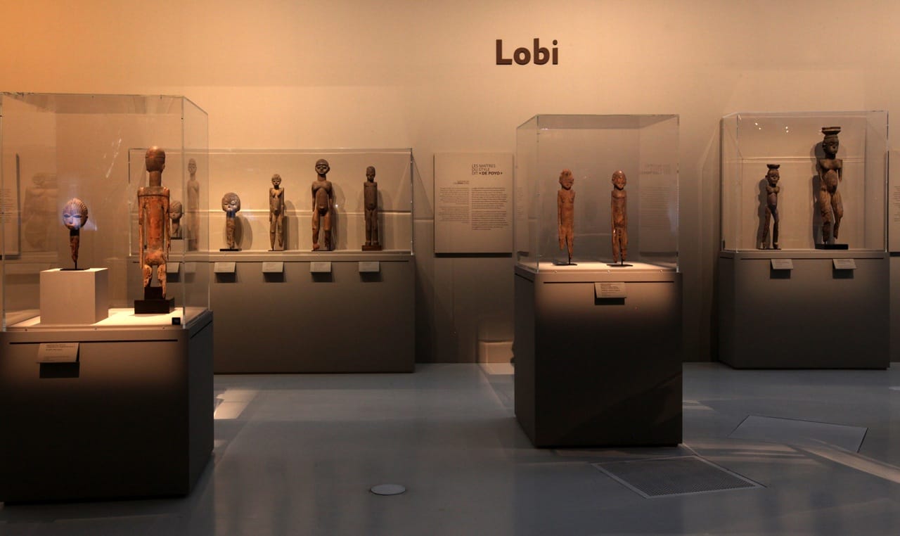 MusÈe du quai Branly. Affiche de l'exposition "Les maÓtres de la sculpture de CÙte d'Ivoire". Du 14 avril au 26 juillet 2015. Galerie Jardin. Vue de l'exposition. RÈunissant prËs de 200 oeuvres historiques et contemporaines, l'exposition met ‡ l'honneur les grands sculpteurs et les Ècoles de sculpture de CÙte d'Ivoire et de ses pays limitrophes. Elle resitue les sculptures dans le contexte religieux et stylistique des Ateliers du 19e et dÈbut du 20e siËcle, notamment chez les SÈnoufo, les Lobi, les Dan ou encore les BaoulÈ, en les considÈrant sous l'angle de leur force esthÈtique et de la singularitÈ de leur crÈateur. L'exposition prÈsente Ègalement des installations et oeuvres d'artistes contemporains: la nouvelle gÈnÈration d'artistes africains ´ transnationaux ª, hÈritiËre des grands artistes du passÈ, met en avant la continuitÈ crÈative des sculpteurs d'Afrique de l'Ouest dans la pÈriode postcoloniale.