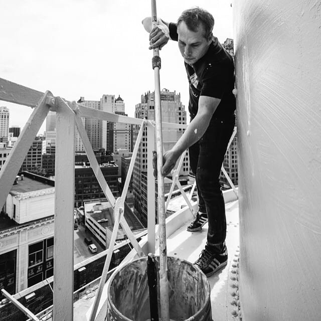 Shepard Fairey wheatpasting a poster on a water tower in Detroit last month. (photo by obeygiant/Instagram)