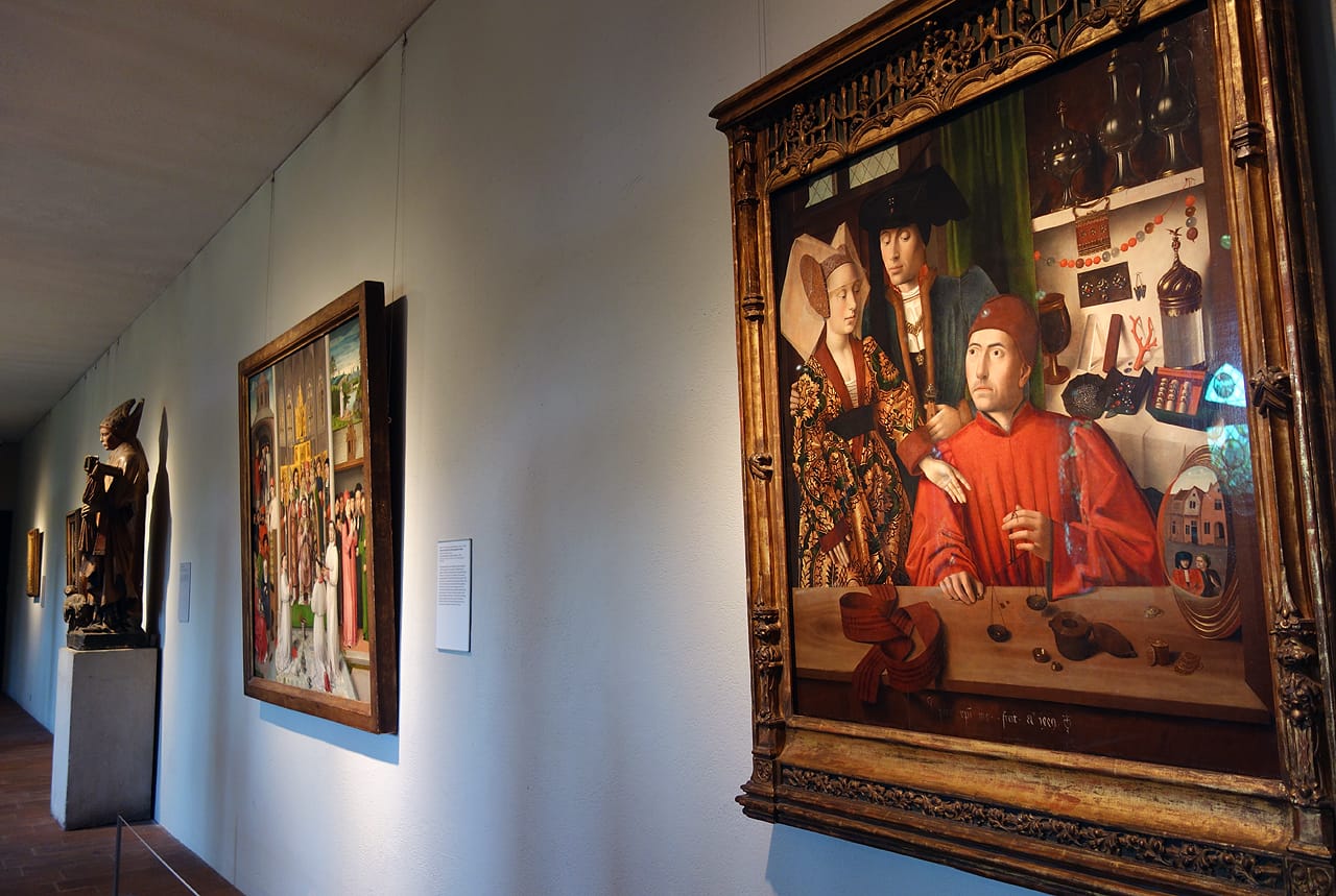 Installation view of 'Treasures and Talismans: Rings from the Griffin Collection,' with at right: Petrus Christus, "A Goldsmith in his Shop" (Netherlandish, 1449), oil on oak panel