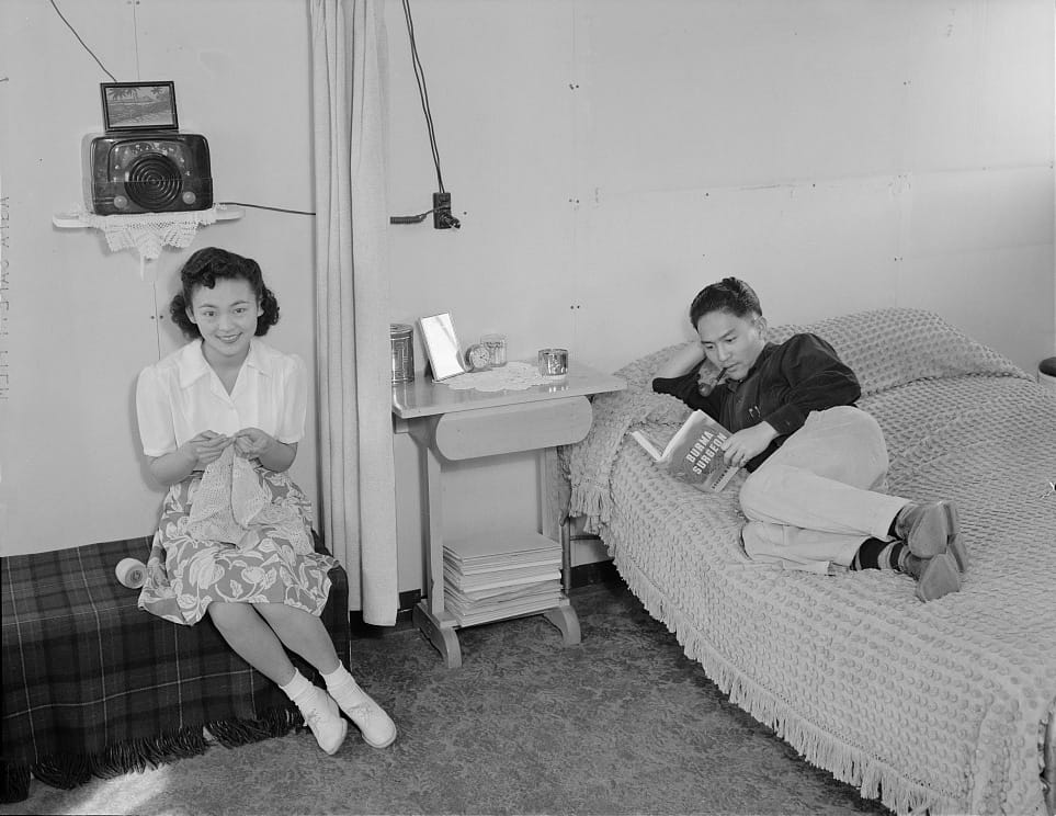 Ansel Adams, "Manzanar, CA, 1943" (1943). Mrs. Shimizu seated with her lacework, and her husband Dennis lying on their bed, reading the newest release by Gordon Seagrave, an American missionary and surgeon (http://www.criticalpast.com/video/65675033599_General-Joseph-Stilwell_Gordon-Seagrave_Naga-hills_Fiji-soldier-on-a-radio), working in the China-Burma-India theater of the war (photograph by Ansel Adams, courtesy the Library of Congress, Prints & Photographs Division [reproduction no. LC-DIG-ppprs-00084])