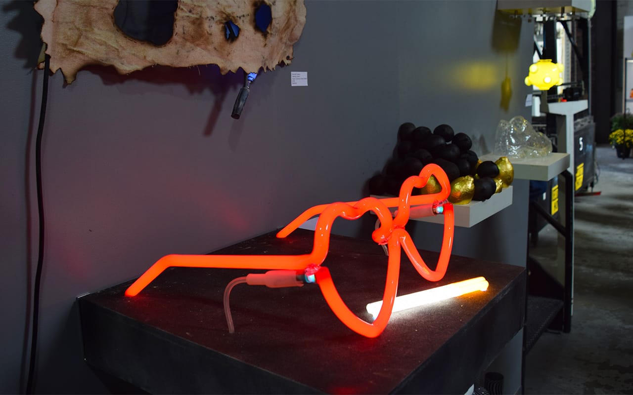 Glass sculptures made on-site — with Kate Hush's neon piece "She-Devil" (2015) in the foreground — displayed at Brooklyn Glass