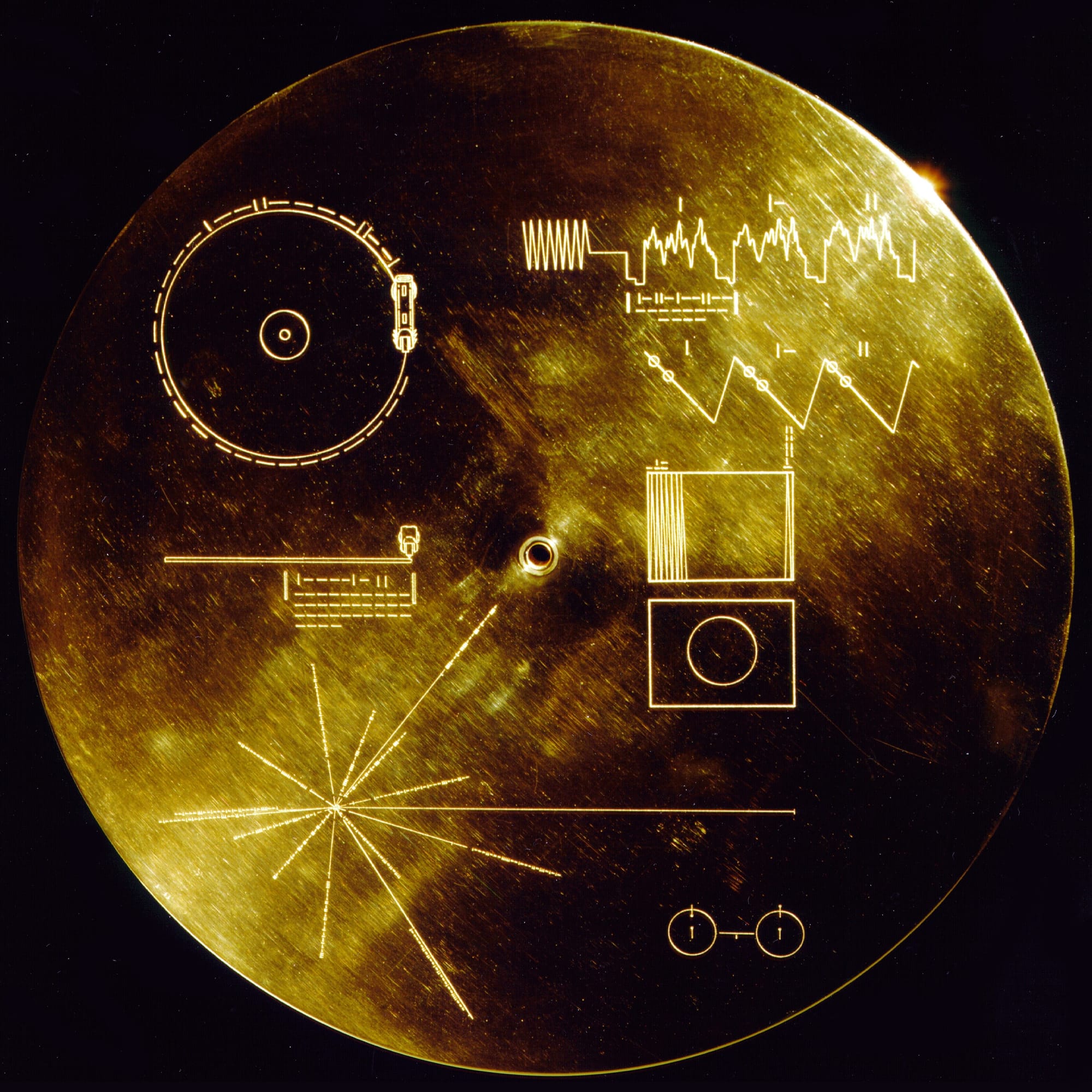 The cover of the Golden Record. This gold aluminium cover was designed to protect the Voyager 1 and 2 "Sounds of Earth" gold-plated records from micrometeorite bombardment, but also serves a double purpose in providing the finder a key to playing the record. By NASA/JPL [Public domain], via Wikimedia Commons