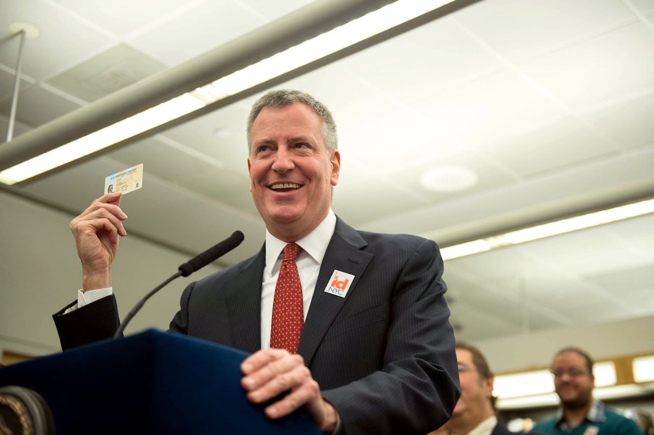 Bill de Blasio holding an IDNYC card (image via Youtube/NYC Mayor's Office)