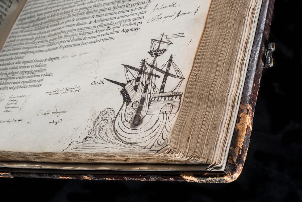 A ship sweeps on the waves at the corner of a page of the complete works of Cicero. John Dee was likely inspired by the adjoining lines of verse: "So huge a bulk glides from the deep with the roar of a whistling wind / Waves roll before, and eddies surge and swirl / Hurtling headlong, it snorts and sprays the foam." (Cicero, 'Opera,' published Paris, 1539–1540) (© Royal College of Physicians / John Chase)