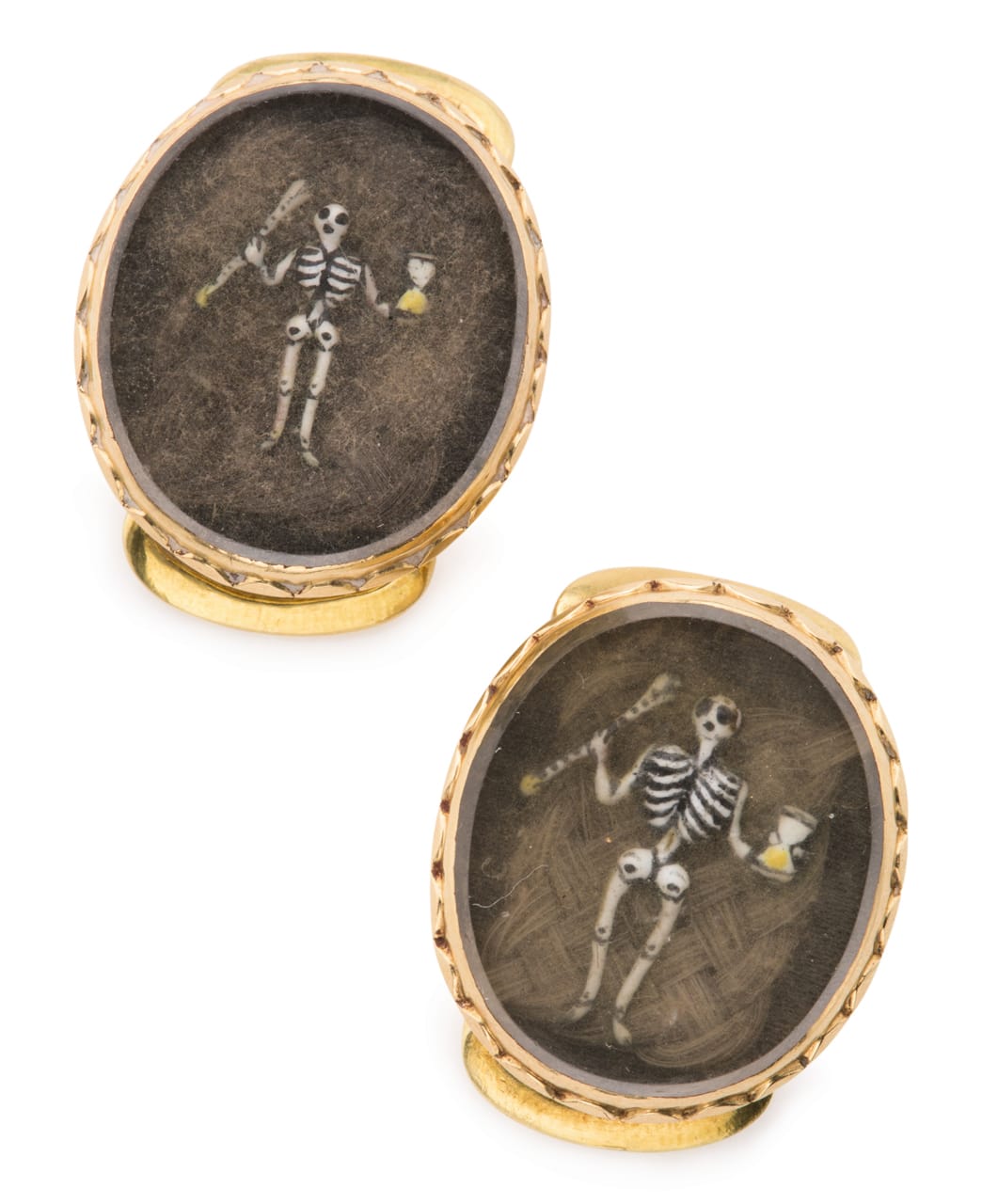 Two matching English gold and hairwork mourning slides (1684), both with enameled skeletons holding an hourglass and an arrow over hairwork, reverse engraved "ob, 28 Jan. Jerrum Gatticre 1684." and with loop attachments.