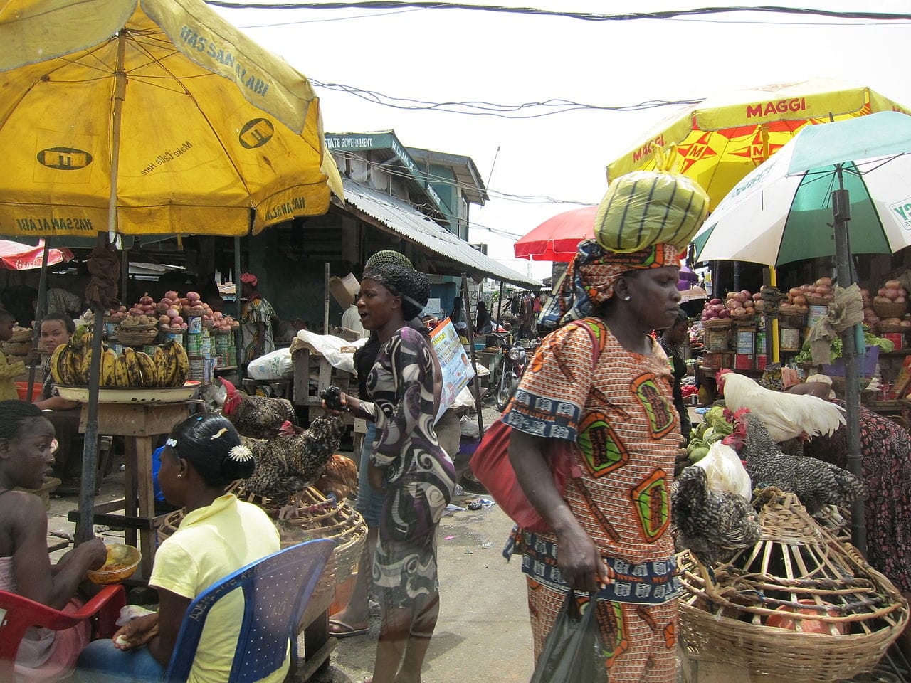 An open-air market in Lagos, with one of the dishes similar to those used in the installation holding bananas at left (photo by Satanoid/Wikimedia)