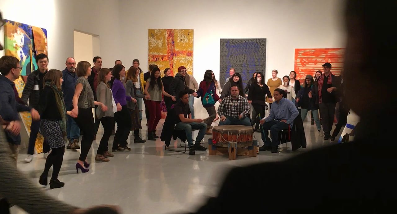 Students, staff, and faculty during the friendship dance; Jason Baerg is on the far right in the hat and scarf (still from video by and © Ardele Lister)