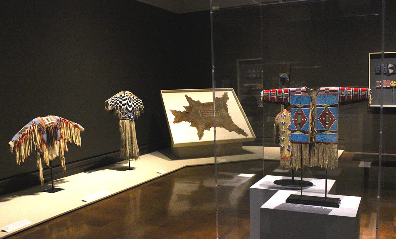 Installation view, 'Indigenous Beauty: Masterworks of American Indian Art from the Diker Collection' at the Toledo Museum of Art, showing garments and domestic objects from the Plains and Plateau region (all photos by the author for Hyperallergic unless otherwise noted)