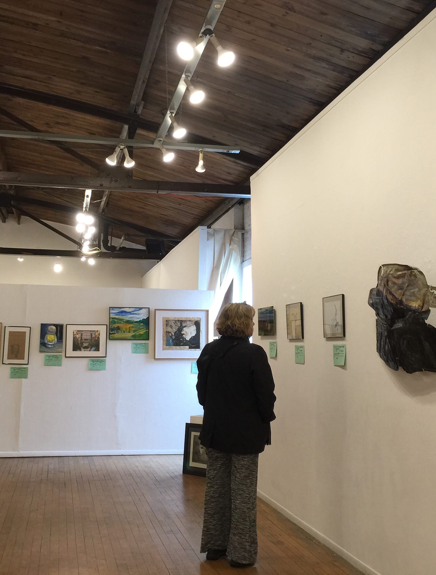 Founded in 1983, the nonprofit Buckham Gallery presents work by area artists, many of them on the faculties of University of Michigan-Flint and Mott Community College. Here, a visitor looks at remaining works from a recent fundraising auction. (click to enlarge)