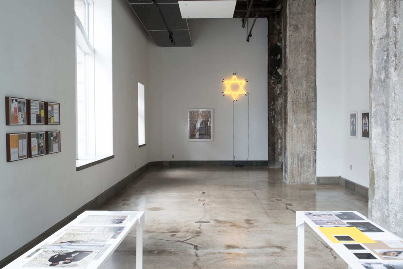 The installation features several signs, including a Jewish star in gold neon, and the Hebrew word for "gold" rendered in white neon. Image courtesy of River House Arts.