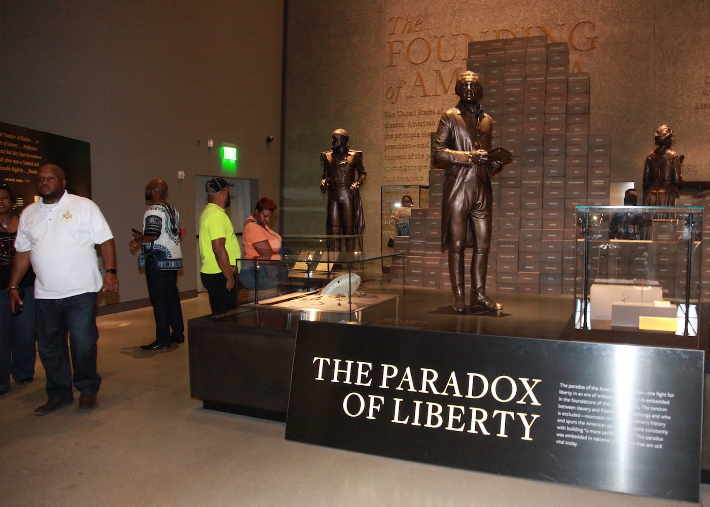 A statue of Thomas Jefferson stands in front of a wall of bricks engraved with the names of enslaved people he owned.