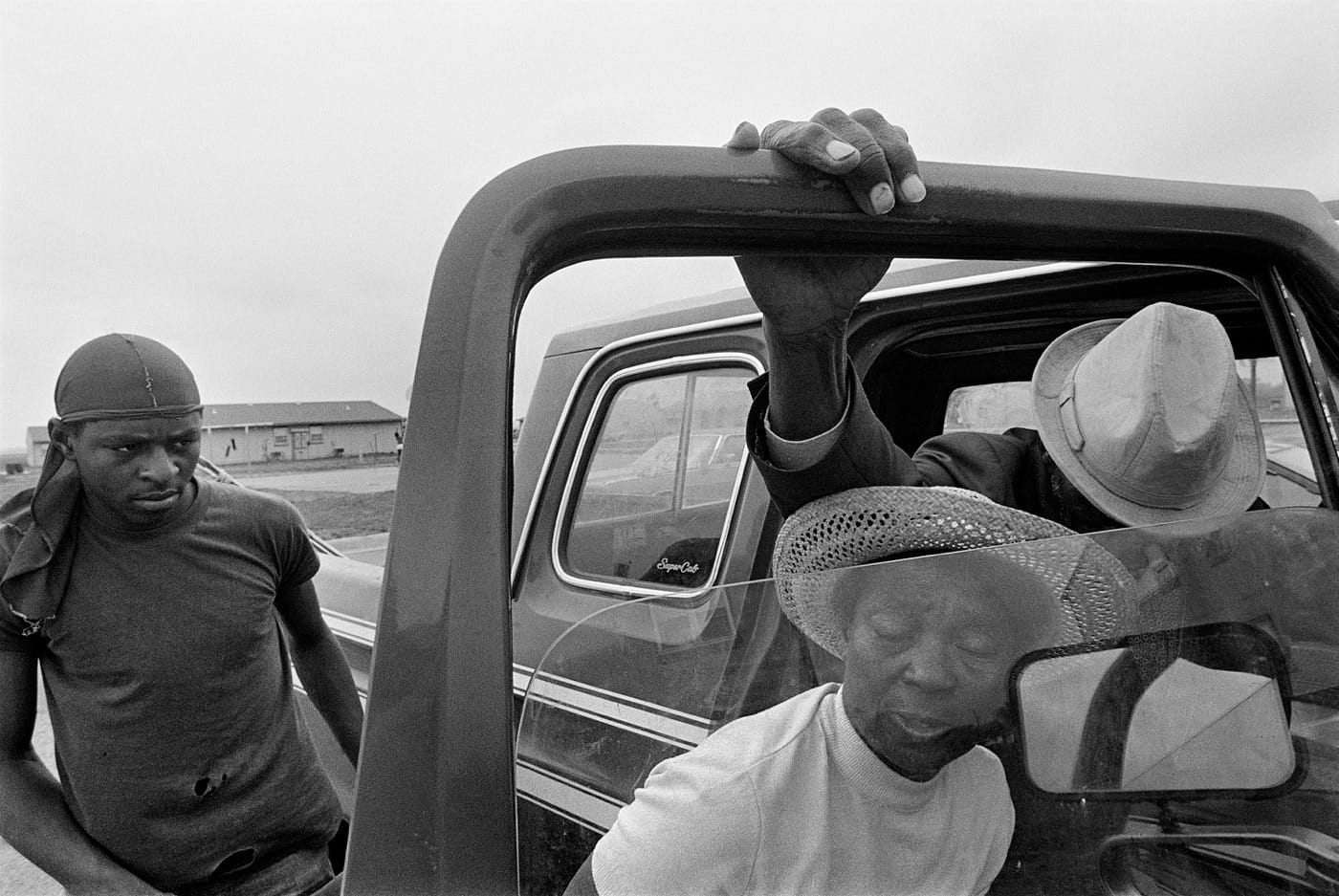 Caption: Porter Lee Davis helps her critically ill husband, Mr. Will, from the cab of their pickup truck. Title: Porter Lee and Mr. Will, Hughes, Arkansas, 1986