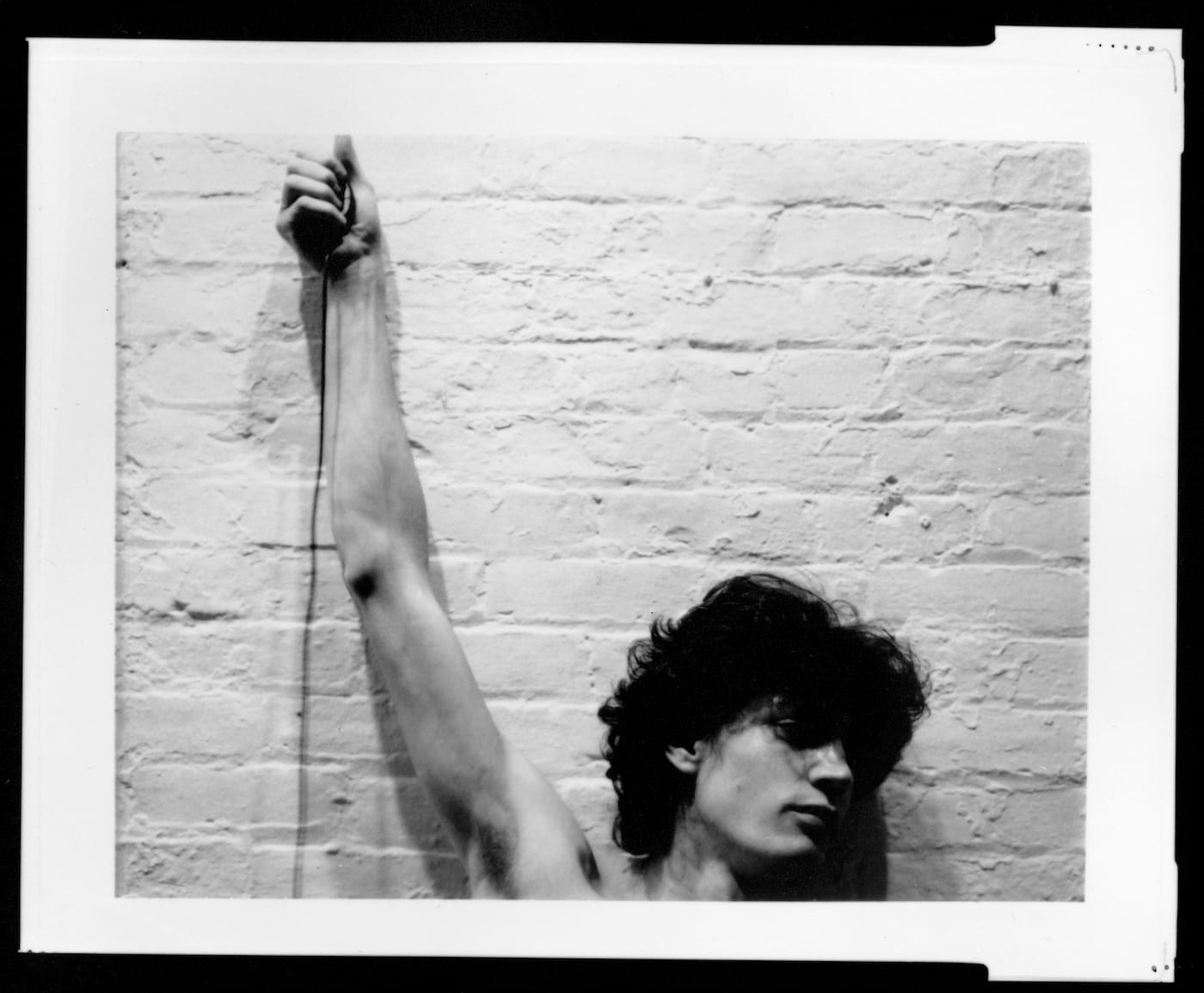 Robert Mapplethorpe, "Self-portrait of Robert Mapplethorpe with trip cable in hand" (1974)