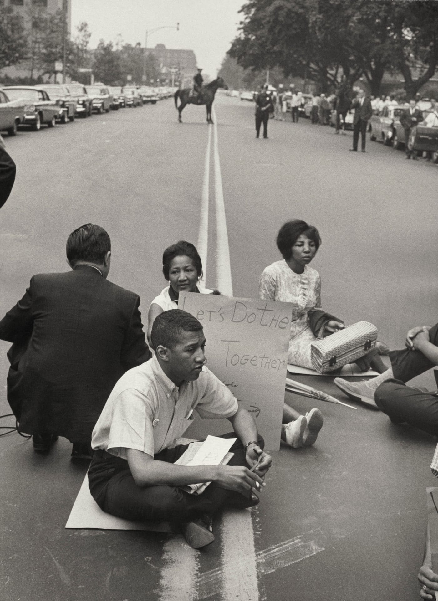 Leonard Freed, "Demonstrators sitting with signs and intentionally blocking traffic during protest on car-lined thoroughfare" (Brooklyn, New York, 1963) (courtesy J. Paul Getty Museum, © Leonard Freed / Magnum Photos)