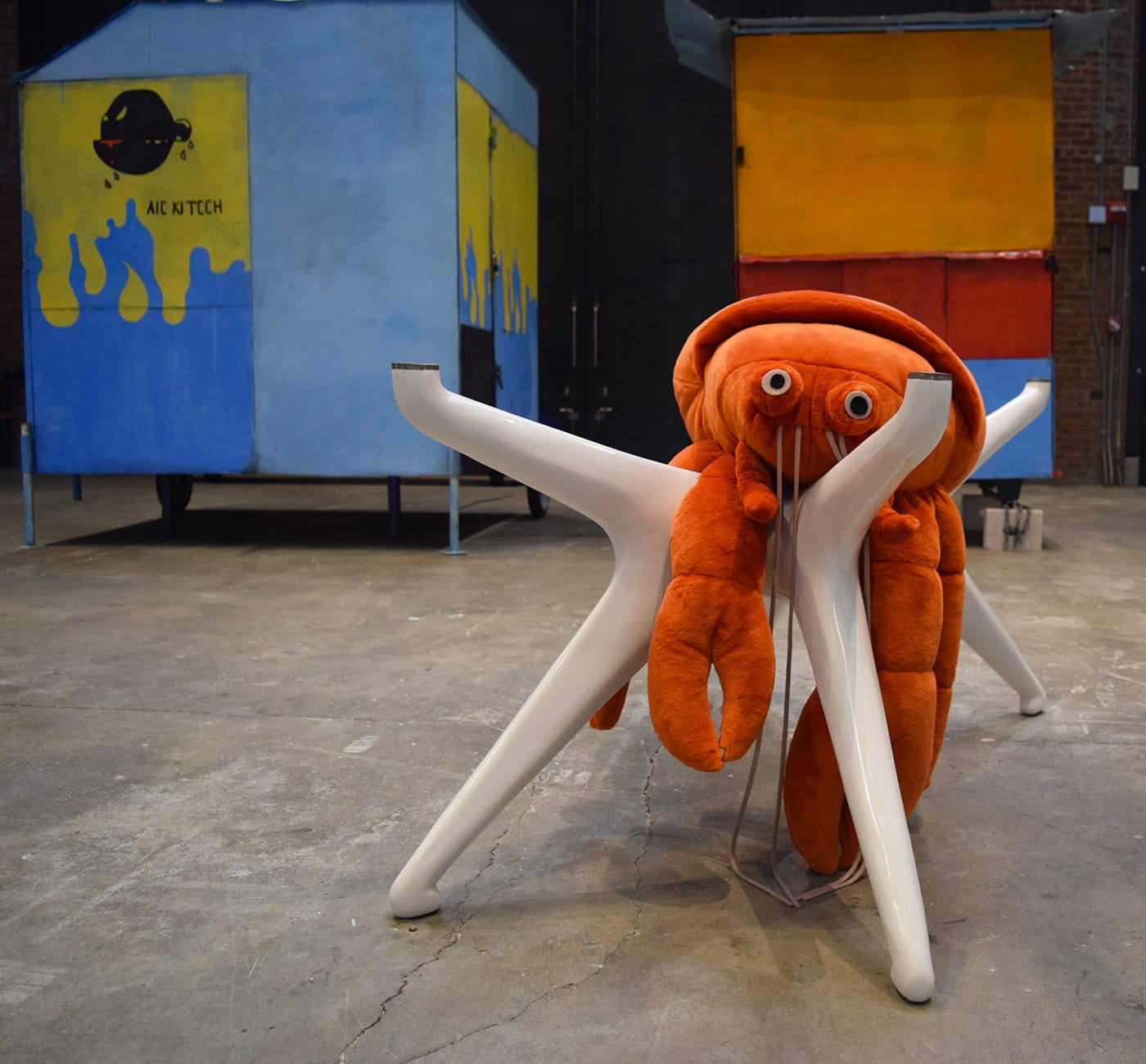Cosima von Bonin, "THE BONIN/OSWALD EMPIRE'S NOTHING #5 (CVB'S SANS CLOTHING. MOST RISQUÉ. I'D BE DELIGHTED & MVO'S ORANGE HERMIT CRAB ON OFF-WHITE TABLE)" (2010), mohair velour, polyfill, styroplast, brass