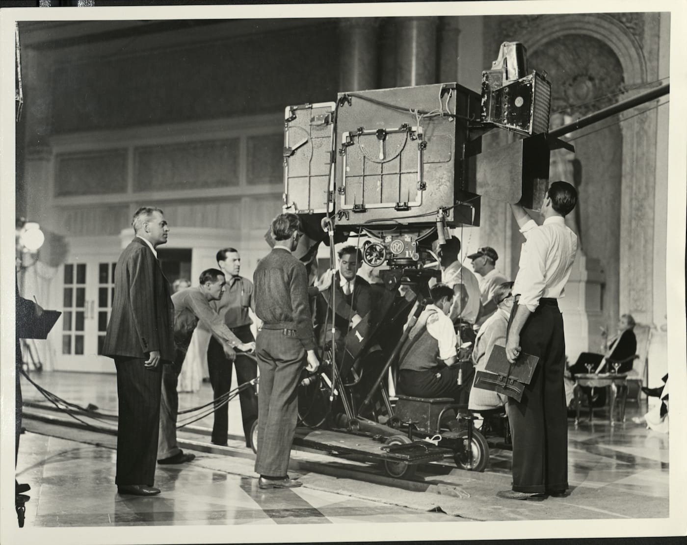 Technicolor camera in its blimp, having studio light attached to the top right and having light shield for the lens, shown in use on the set (Technicolor Corporate Archive, courtesy George Eastman Museum)