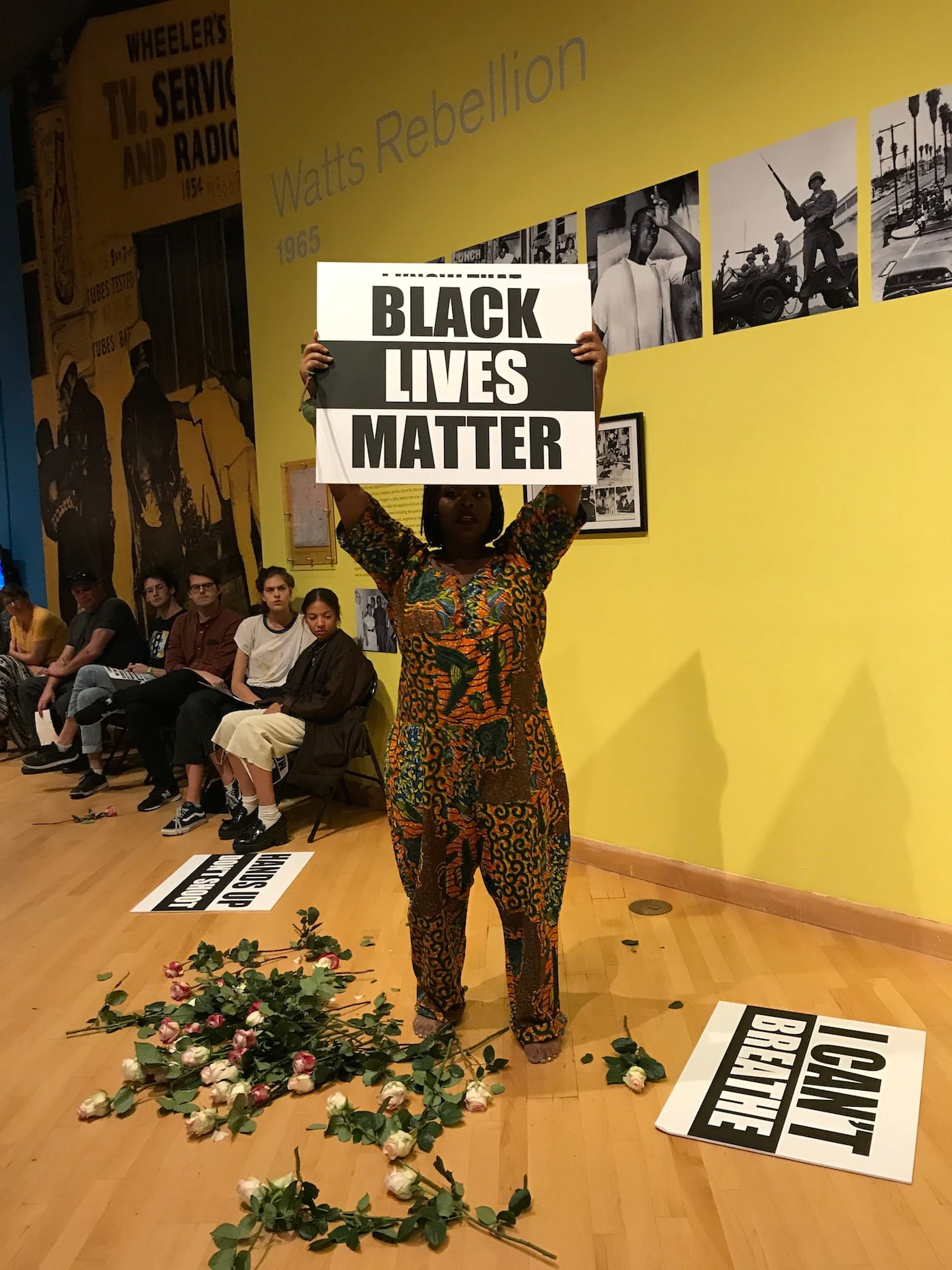 Black Lives Matter co-founder Patrisse Khan-Cullors holds a protest sign during her performance "Remembering '92."