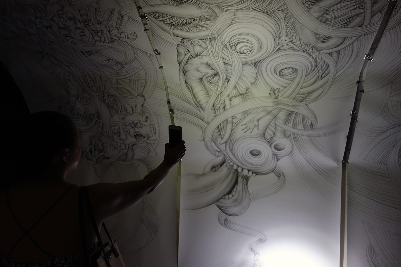 Installation view of ink drawings by Eeva Honkanen, illuminated by iPhone flashlight