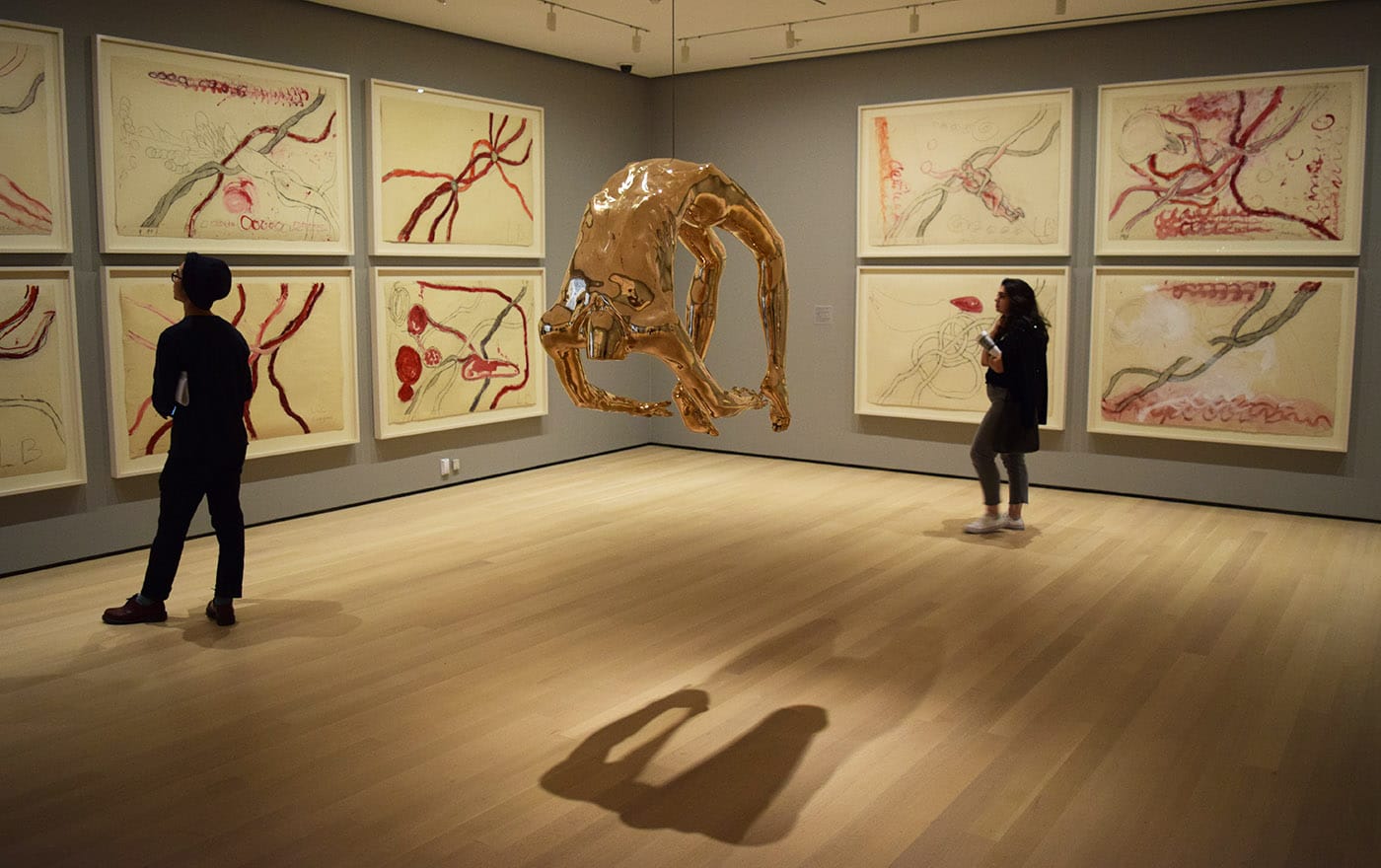 Installation view of Louise Bourgeois: An Unfolding Portrait at the Museum of Modern Art with "Arch of Hysteria" (1993), bronze, polished patina at center and works from the installation set À l'Infini ("To Infinity," 2008) in the background
