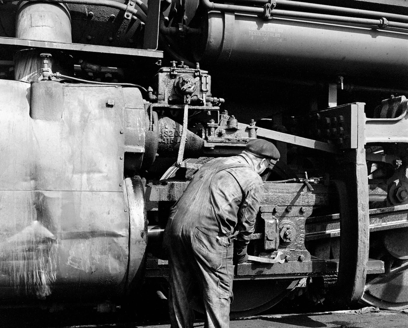 Jim Shaughnessy, "Baltimore Ohio mechanic adjusts cylinder crosshead of a locomotive, Connellsville, Pennsylvania" (1956) (courtesy the artist and Thames & Hudson)
