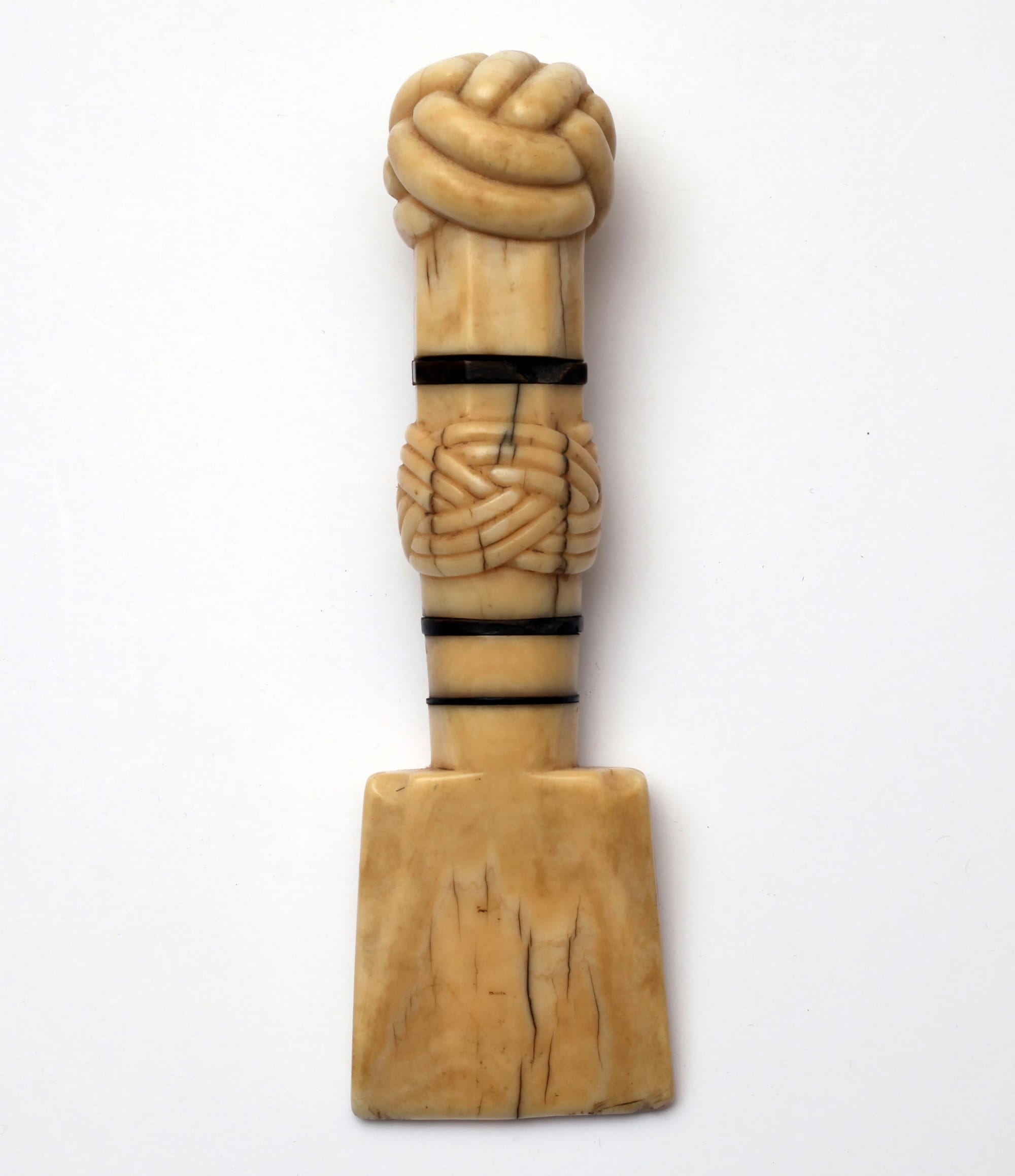 Seam rubber (19th century), carved sperm whale ivory with right whale baleen trim decorated with Monkey’s Fist and Turk’s Head knots on the handle (photographed in <em>The Ashley Book of Knots</em> between pages viii and ix, collection of Phoebe Chardon, courtesy New Bedford Whaling Museum)
