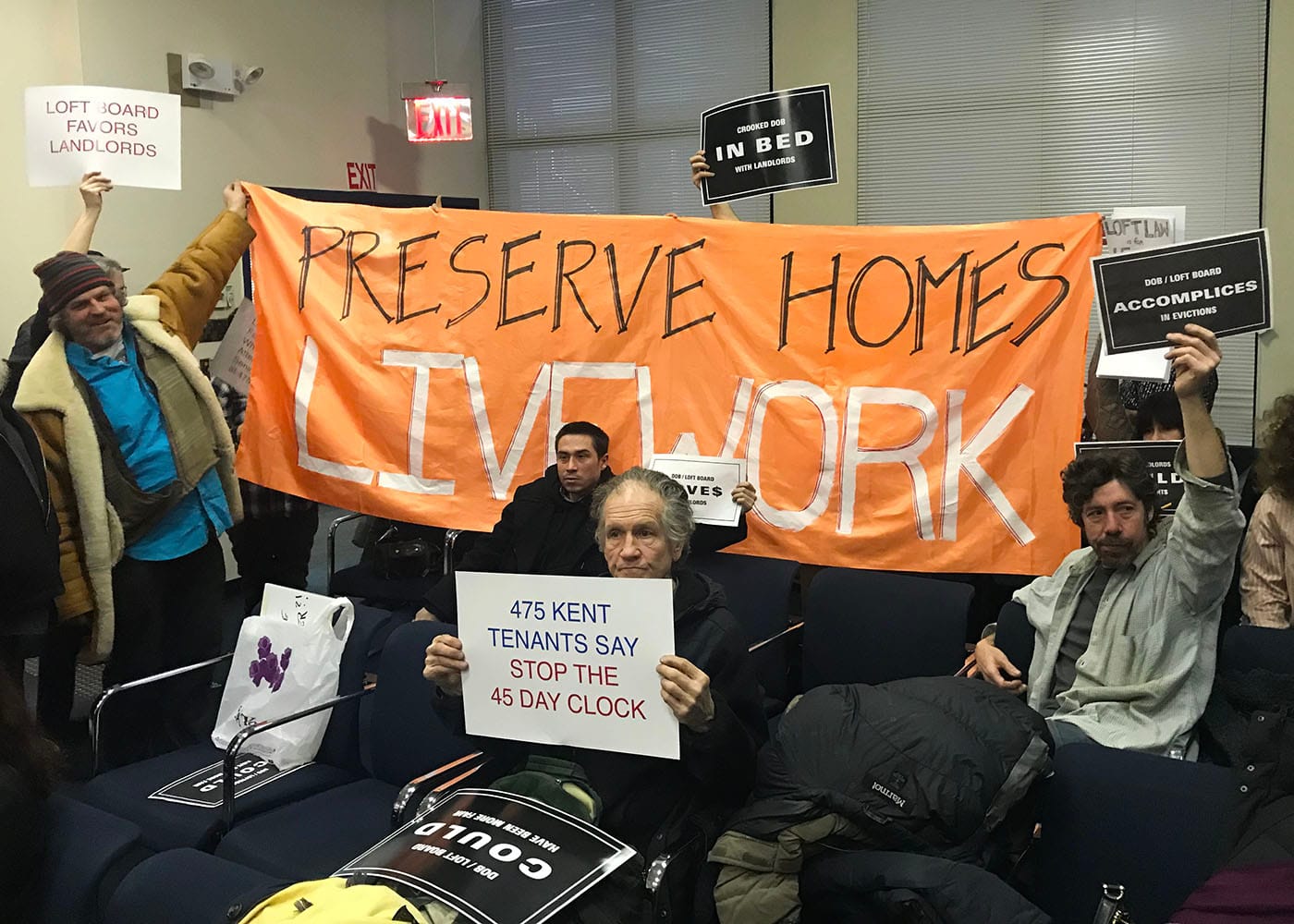 Protesters at a public meeting of New York City's Loft Board on January 18, 2018 unfurled a banner after the meeting concluded. (all photos by the author for Hyperallergic)