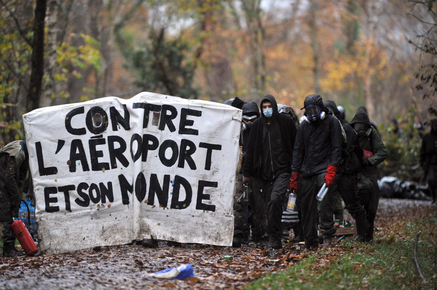 ZAD residents stand behind a barricade that reads "No to the airport and its world."(photo courtesy John Jordan)