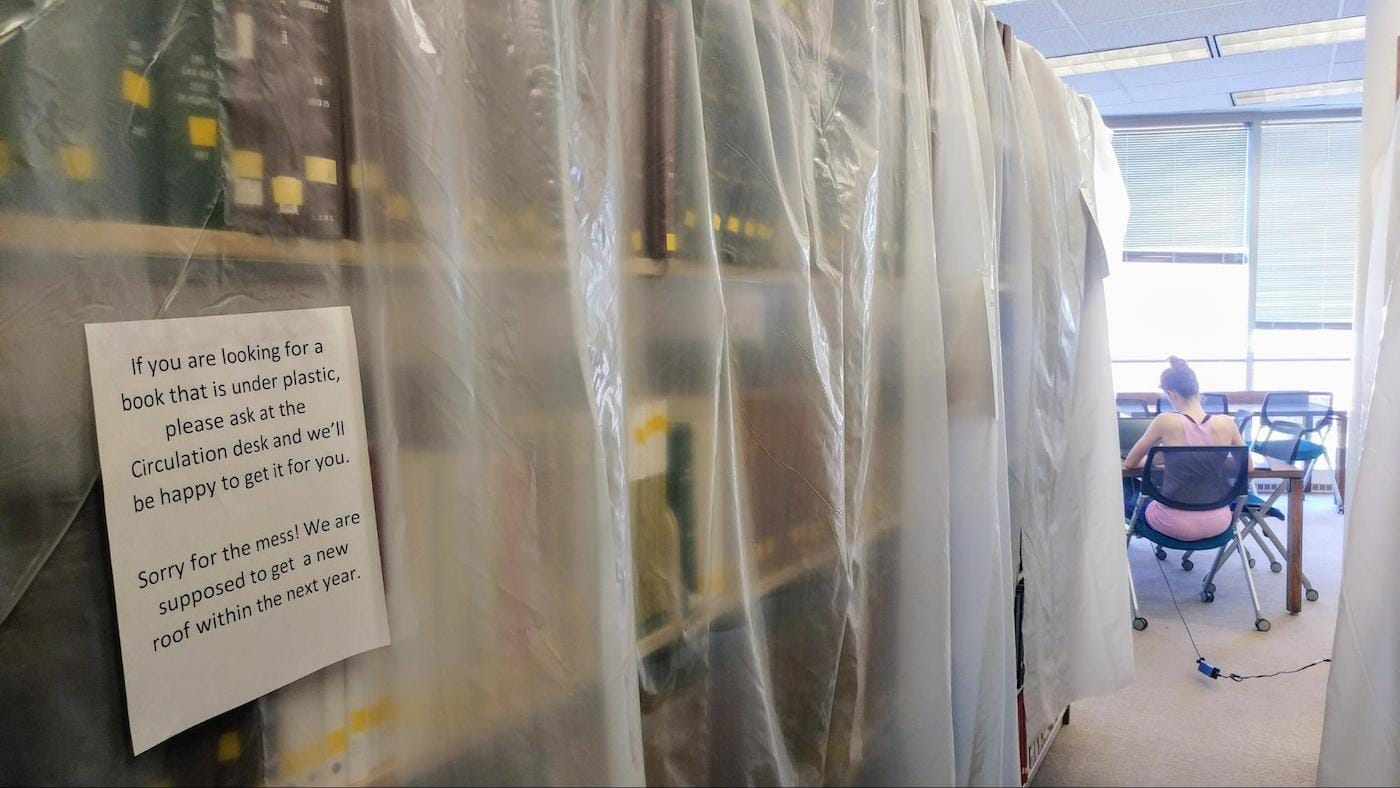 Shelves at UNC’s Sloan Art Library covered in plastic sheeting to protect books from active roof leaks. The sign reads: “If you are looking for a book that is under plastic, please ask at the Circulation desk and we’ll be happy to get it for you. Sorry for the mess! We are supposed to get a new roof within the next year.” (photo by the author)