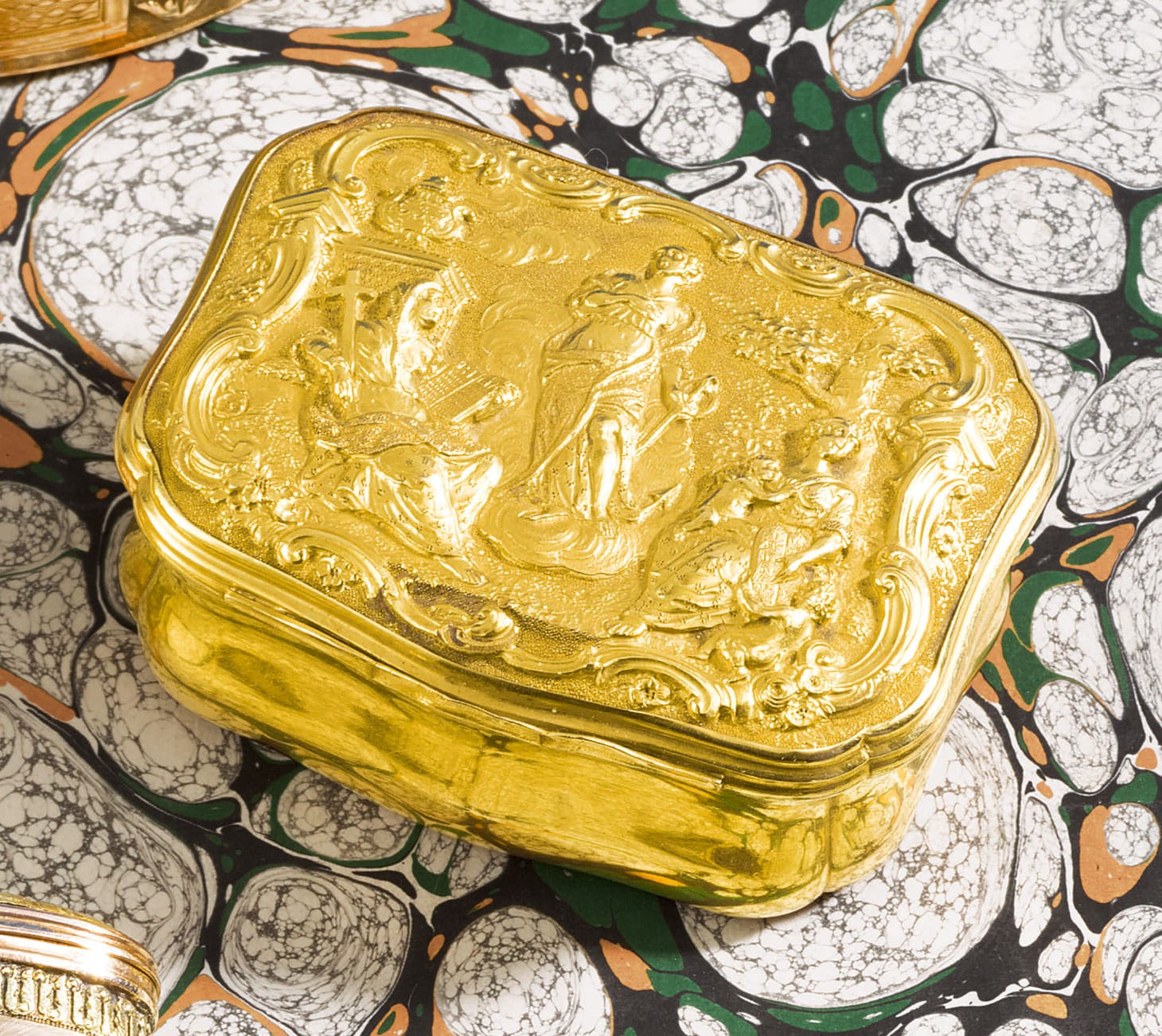 A Dutch gold snuff box, Jacobus de Gilde, Amsterdam (1761), the hinged cover finely chased with figures of Faith seated with cross and bible, Hope standing with anchor on clouds, and Charity seated with two infants, landscape background with incense burner, all within rococo frame, marked inside base, and with later control mark, length 2 1/4 inches (image courtesy Sotheby's)