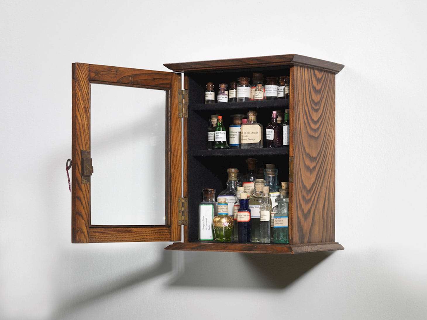 Susan Hiller, "Sa Testa: Homage to Joseph Beuys" Edwardian mahogany cabinet with lock and key, glass-fronted, containing 30 bottles of water collected from sacred springs, holy wells, etc. 6.3 x 9 x 11 inches (image courtesy TEFAF)