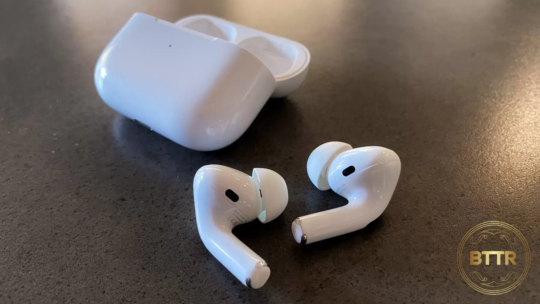 The AirPods pro sitting out in front of the case on a concrete table