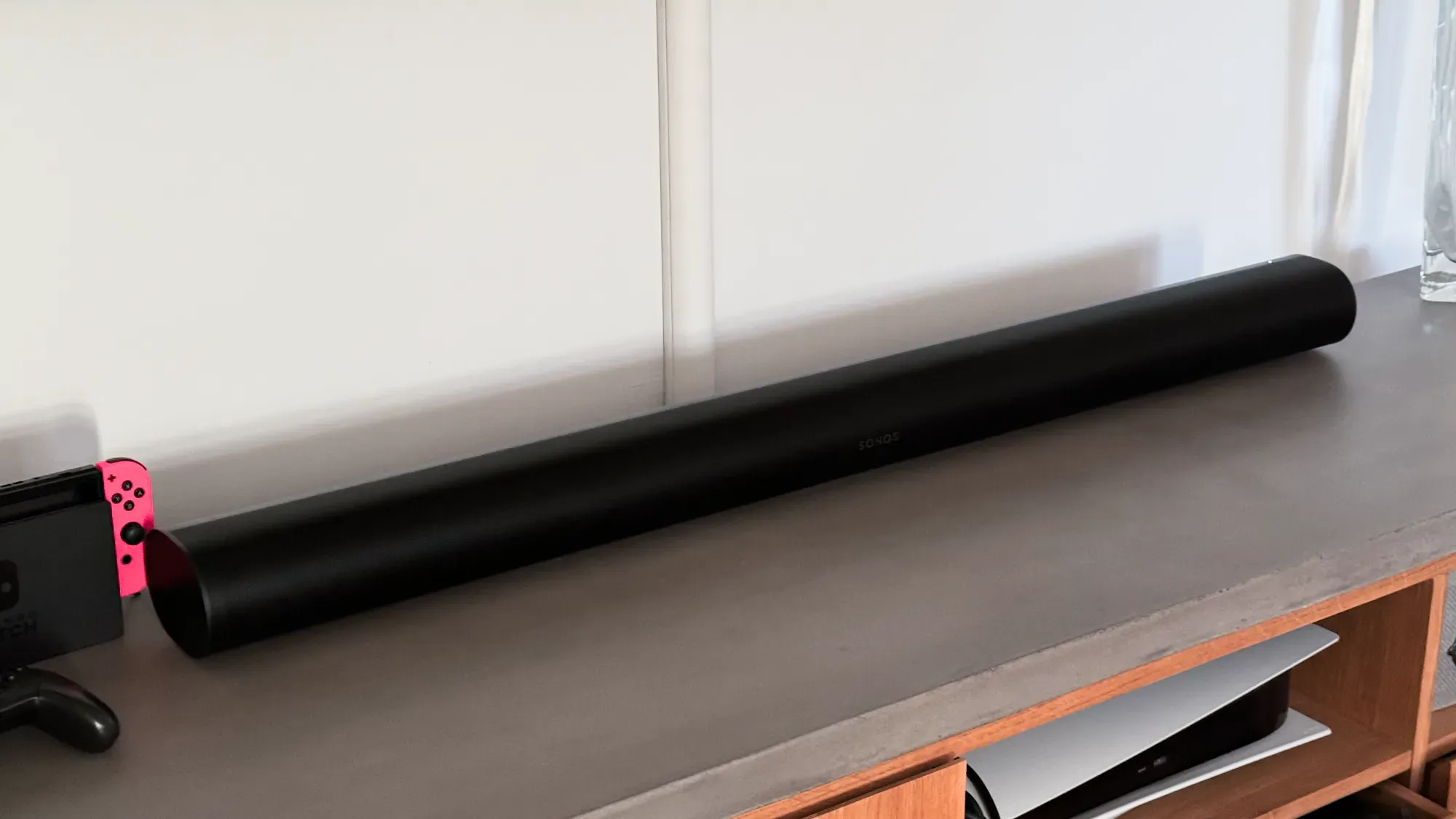 Sonos Arc on a concrete TV entertainment unit next to a Nintendo Switch and below a wall mounted TV