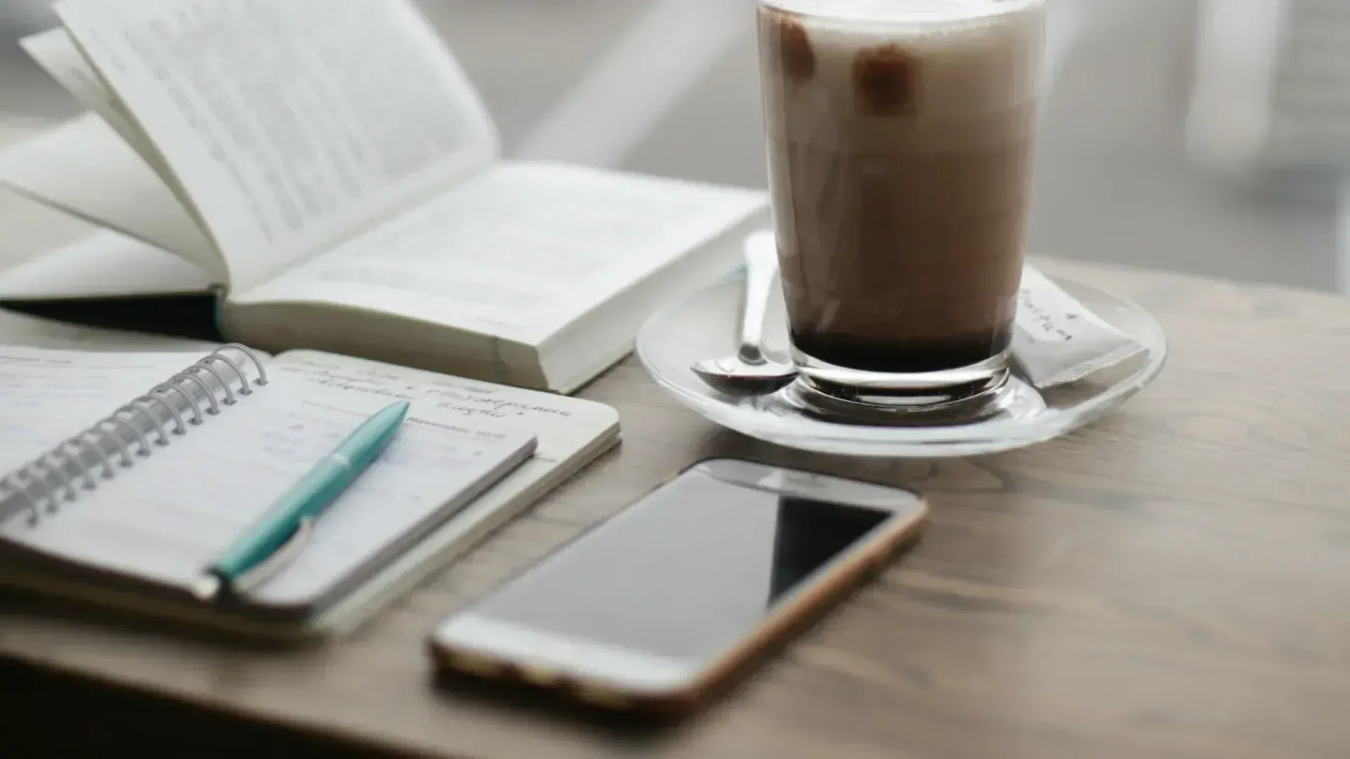 A budget phone on a desk in front of a cup of coffee
