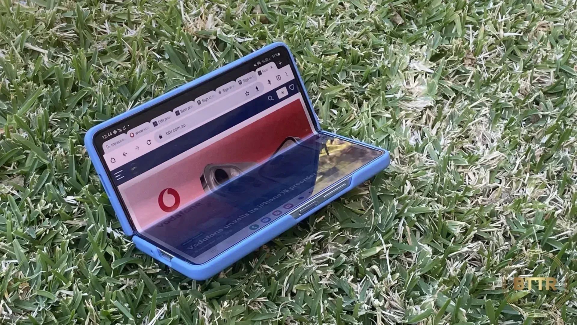 The Galzy Z Fold 5 half folded sitting on grass