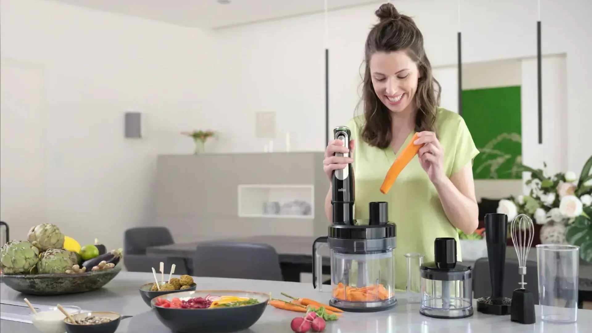 A woman using a stick blender with a food processor attachment