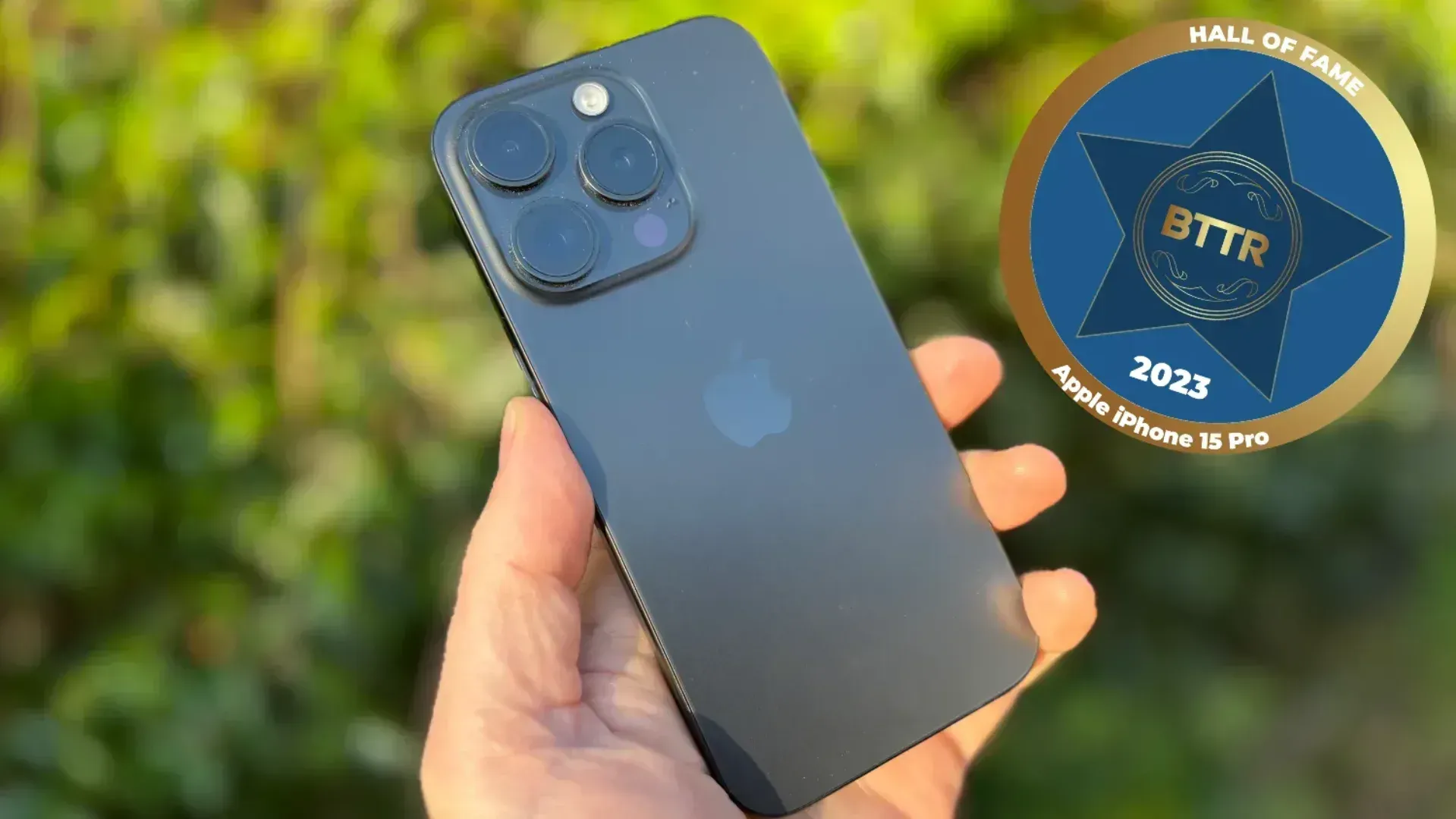 iPhone 15 Pro in hand with a hall of fame badge