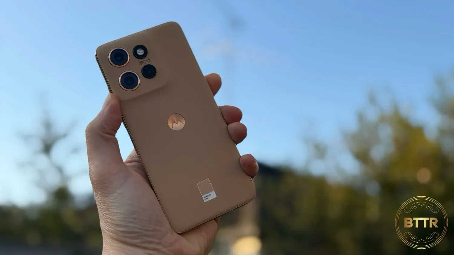 Holding the Edge 50 Neo in hand with a blue sky in the background