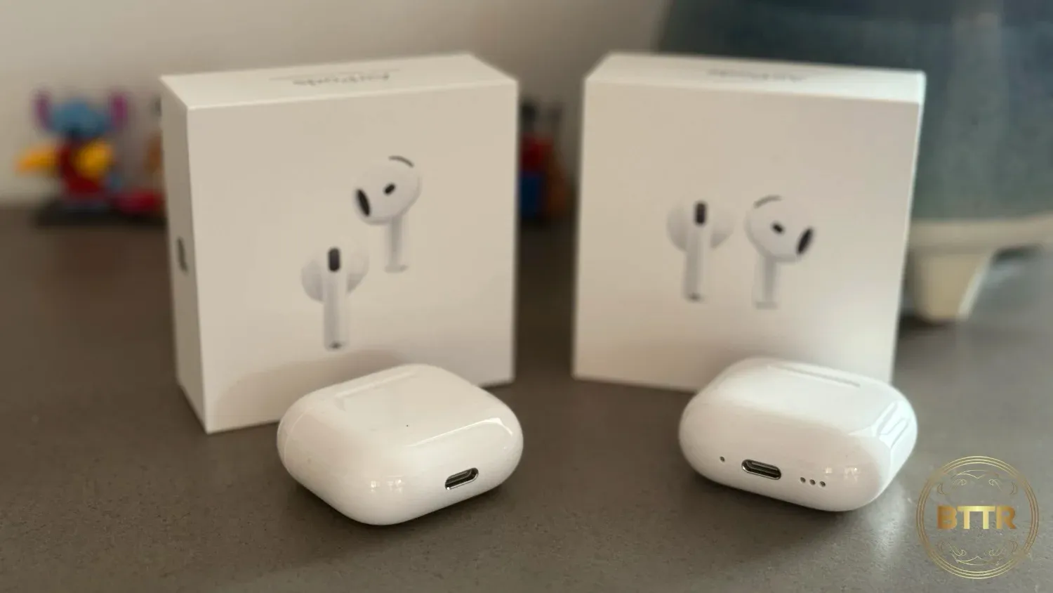 The AirPods 4 unboxed in front of their boxes.