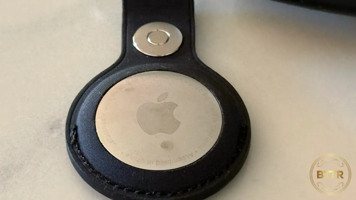 Close up of an AirTag's shiny side, in a keyring accessory