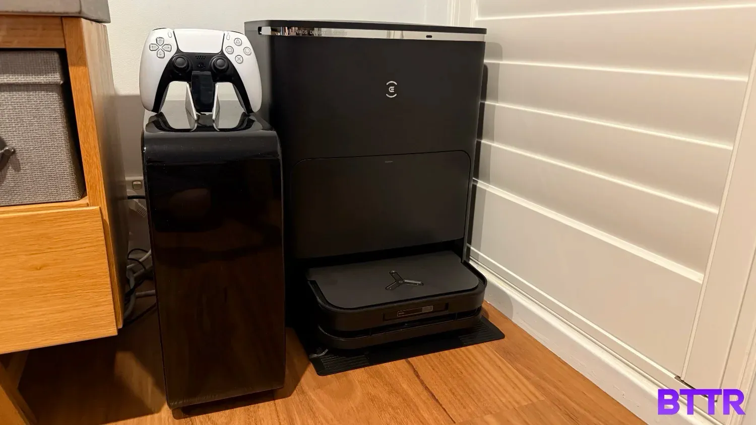 The X5 Pro Omni in the base station, next to a subwoofer with a PS5 controller