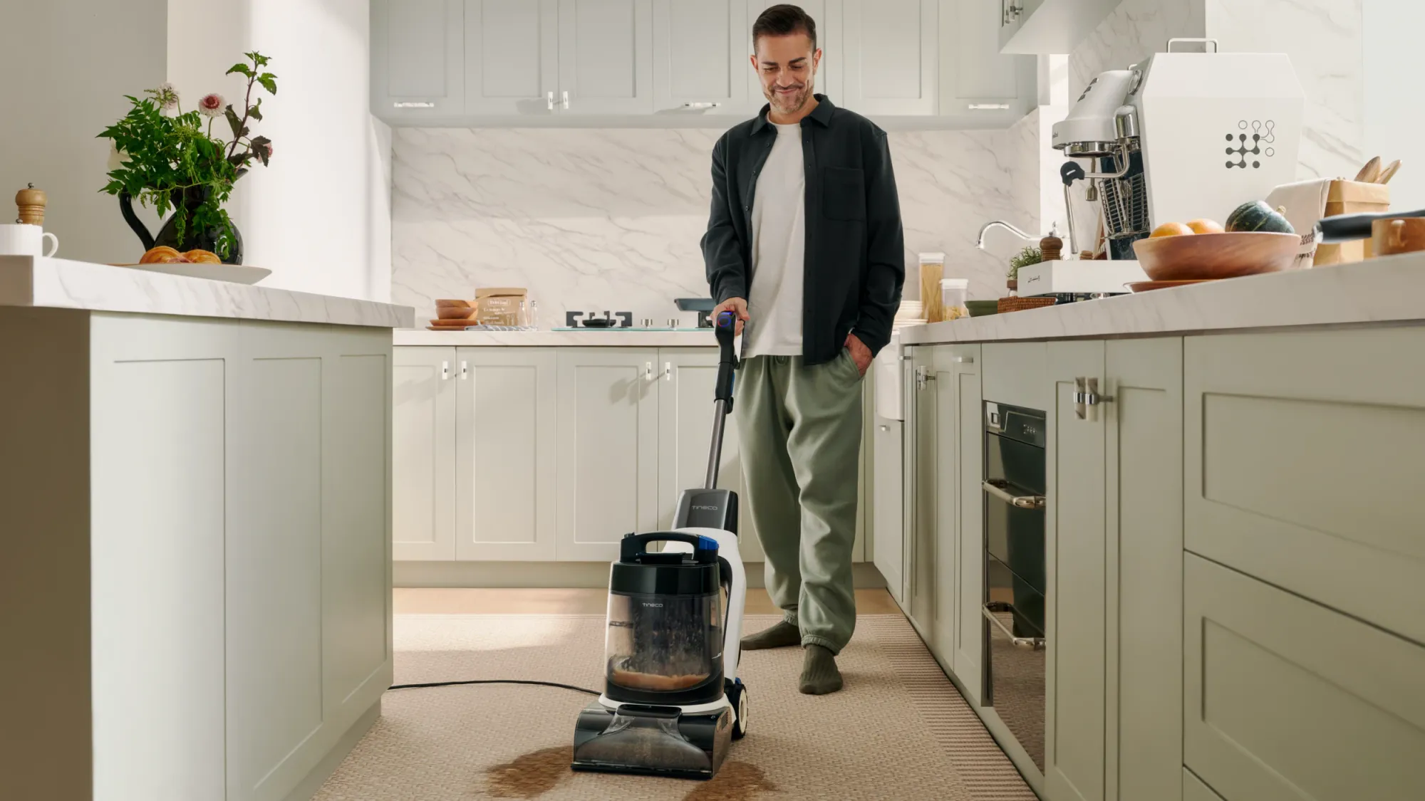 A man cleaning a carpet in a kitchen with the new Tienco Carpet One Cruiser. Who has carpets in a kitchen?