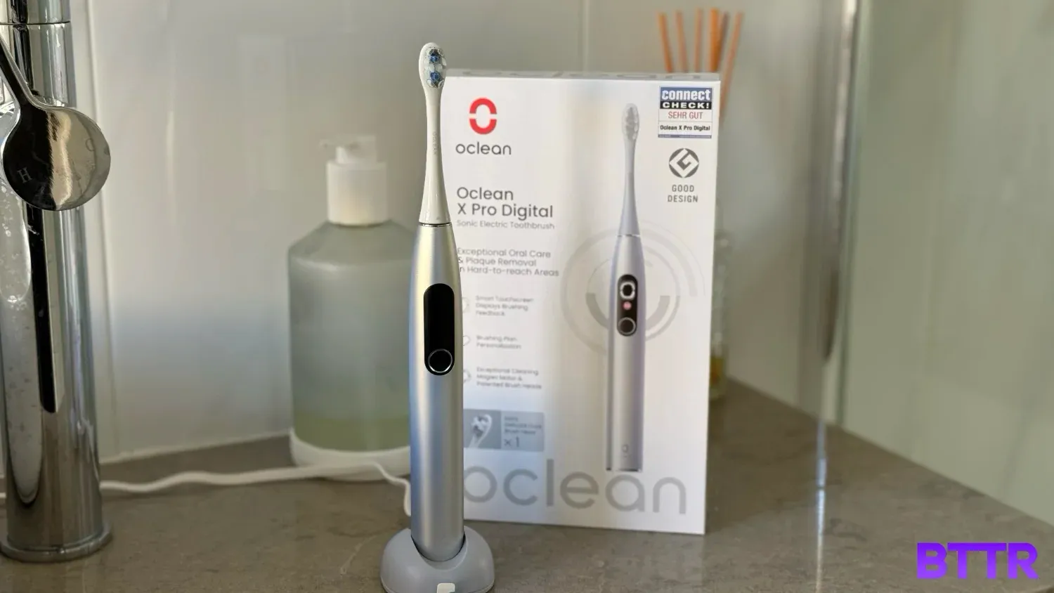 The Oclean X Pro Digital on my bathroom counter in the charger with the box nearby