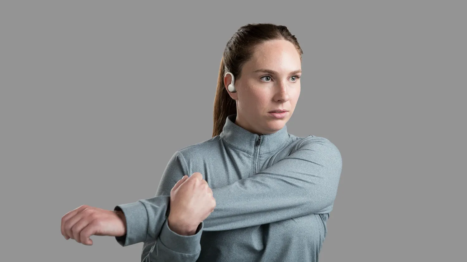A woman stretching while wearing the SoundForm ActiveFit